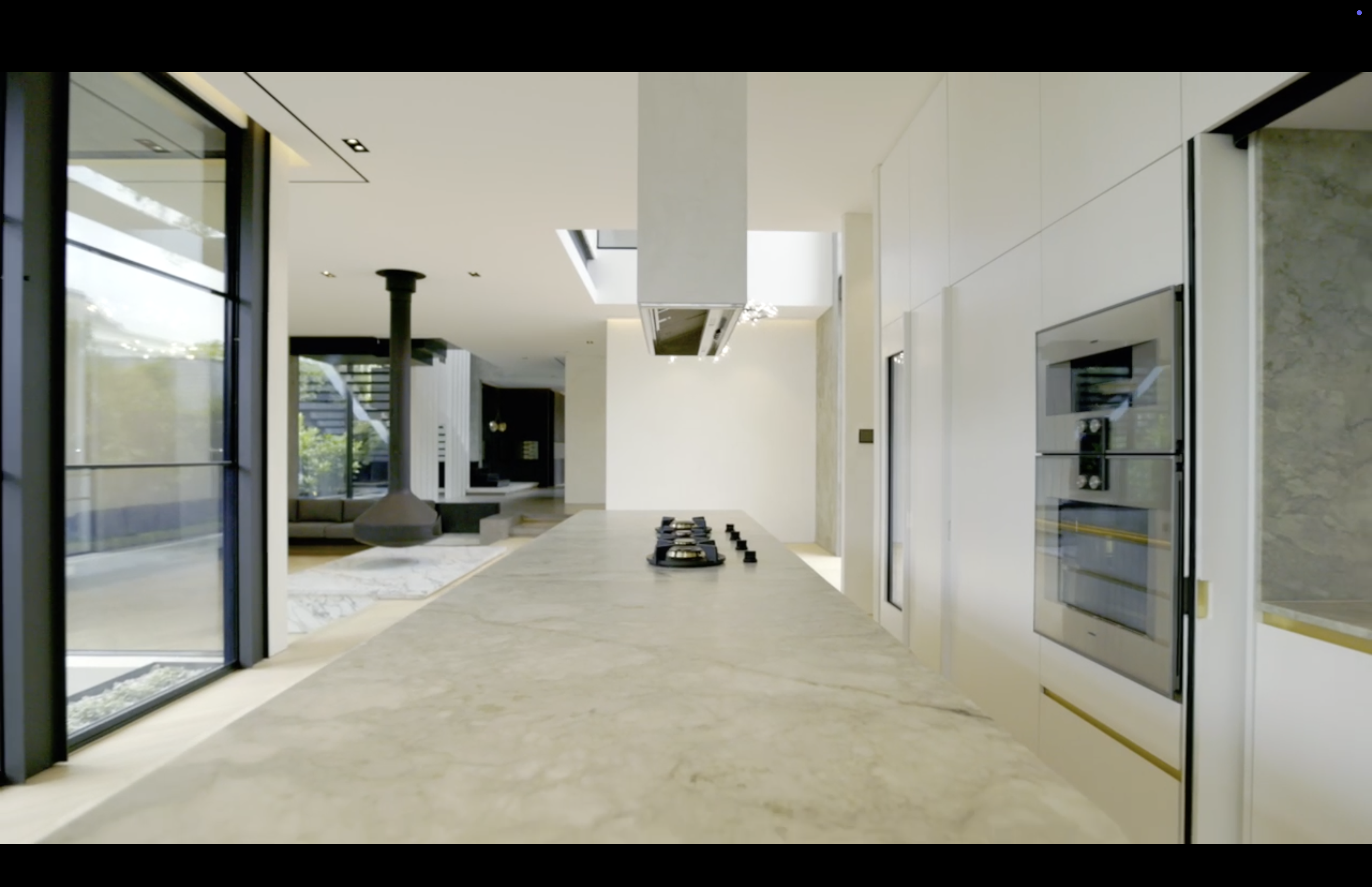 Modern kitchen and living area with marble bench and bright natural light